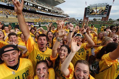 Excited crowd of students on the football field cheering in their Line jerseys