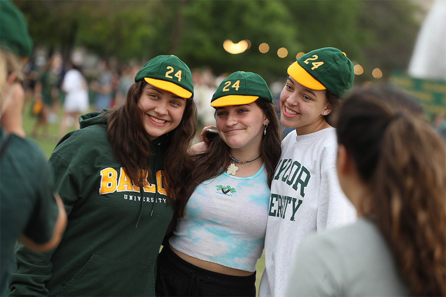 Smiling students outside wearing Baylor shirts and green and gold slime caps